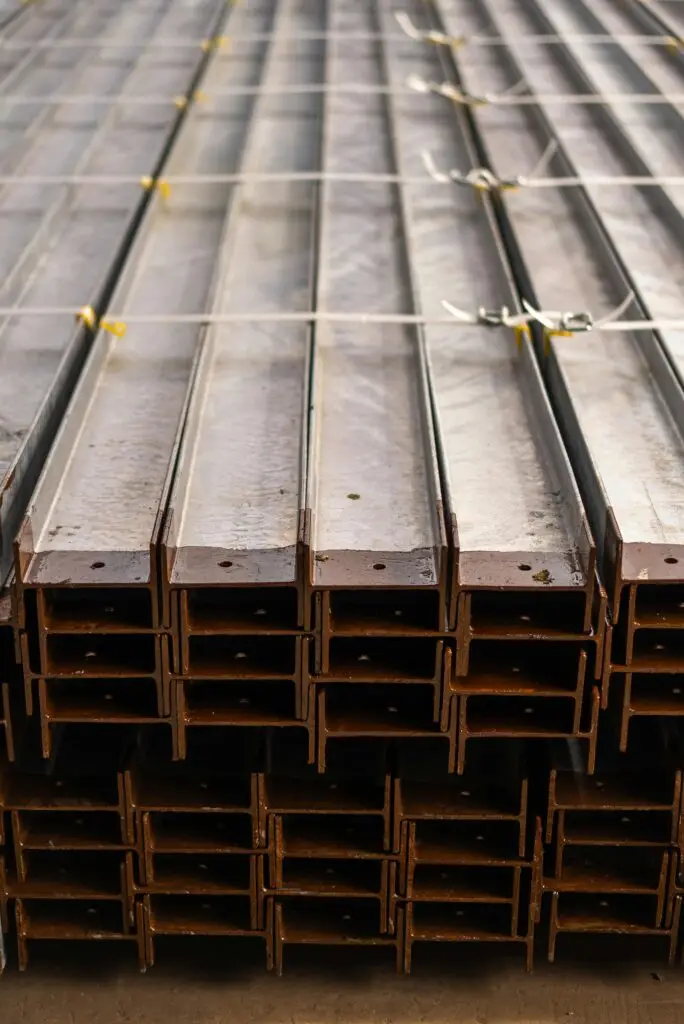 Close-up of neatly stacked steel beams in a warehouse, showcasing metal texture and industrial symmetry.
